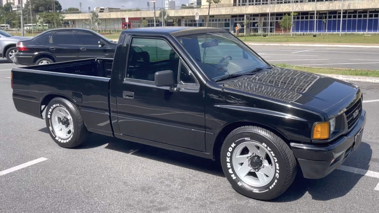 Front three-quarter view of a black 1990s Isuzu pickup in a parking lot.