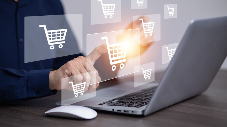 Person using a laptop for online shopping with shopping cart icons floating around the image