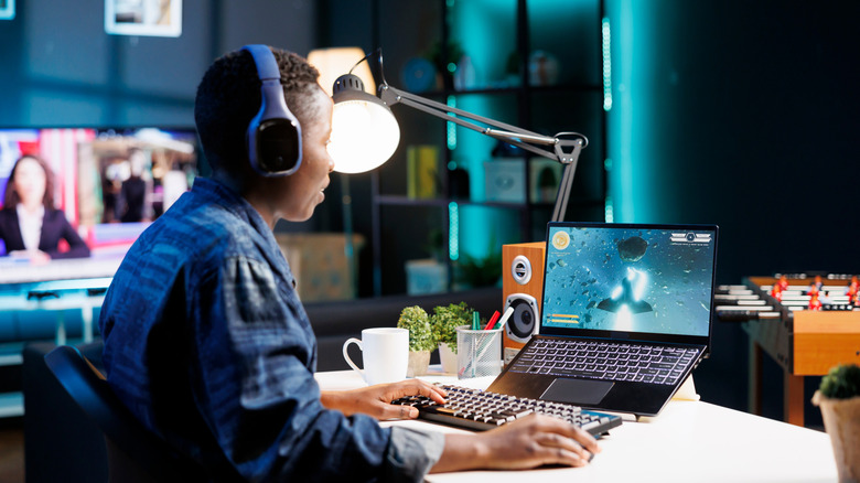 Woman gaming on laptop in dimly lit room