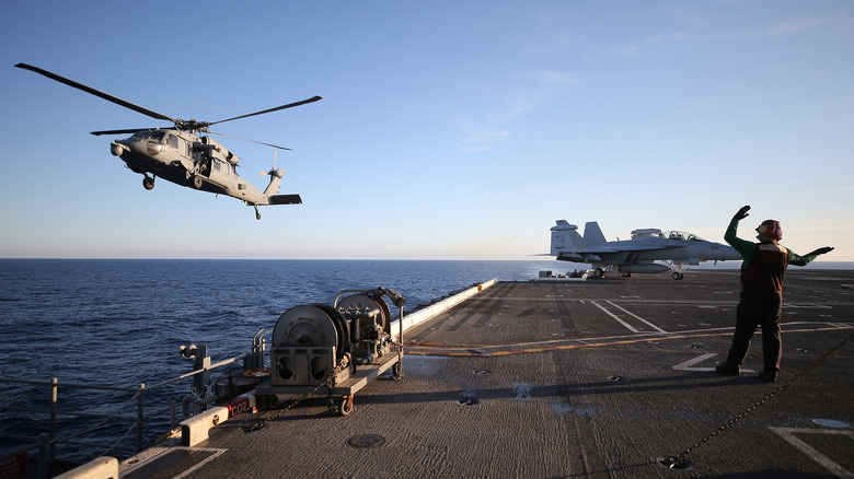 A U.S. Navy helicopter preparing to land on the flight deck of the USS Nimitz.
