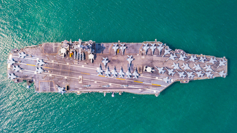 Top-down aerial view of a U.S. Navy aircraft carrier at sea loaded with planes.
