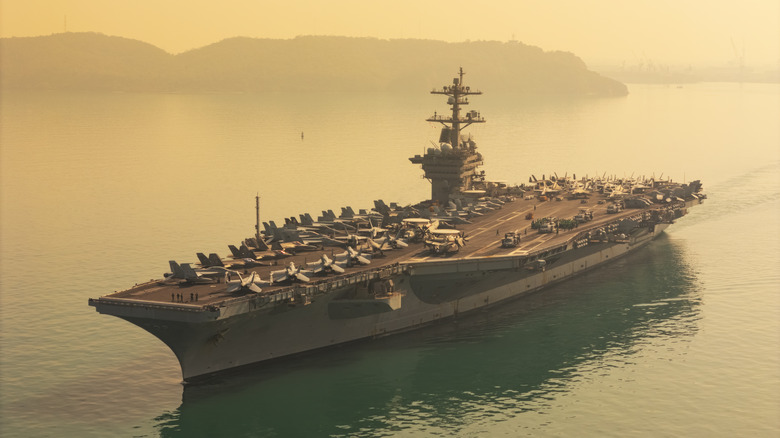 A massive aircraft carrier at sea during sunset
