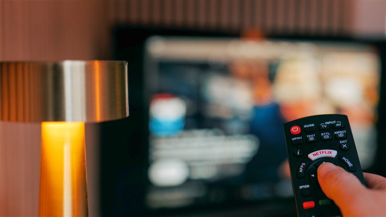 First person view of using a remote to control a blurred smart TV.