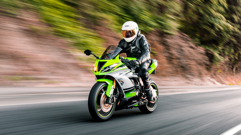 Rider driving a Kawasaki motorcycle on a road.