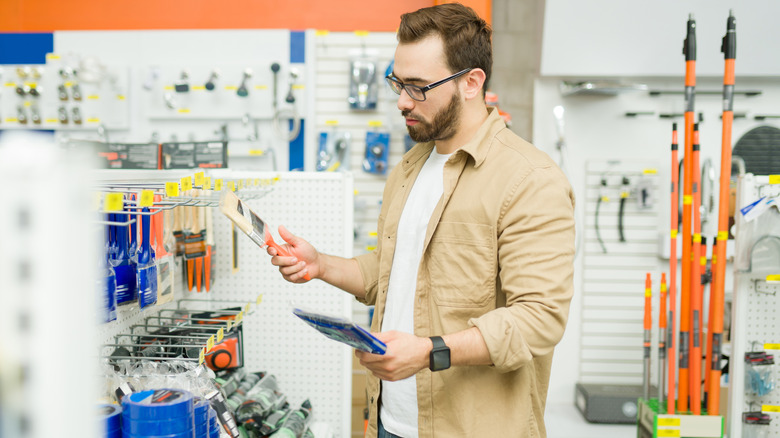 Person in paint isle at home improvement store hold brush