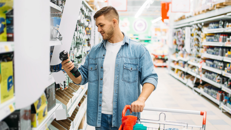 Person shopping at a home improvement store holds drill
