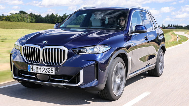 BMW X5 driving at speed, closeup to obscure the exact make of the vehicle