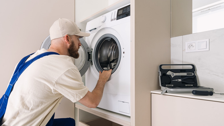 Dryer technician examining a dryer in a home's laundry space