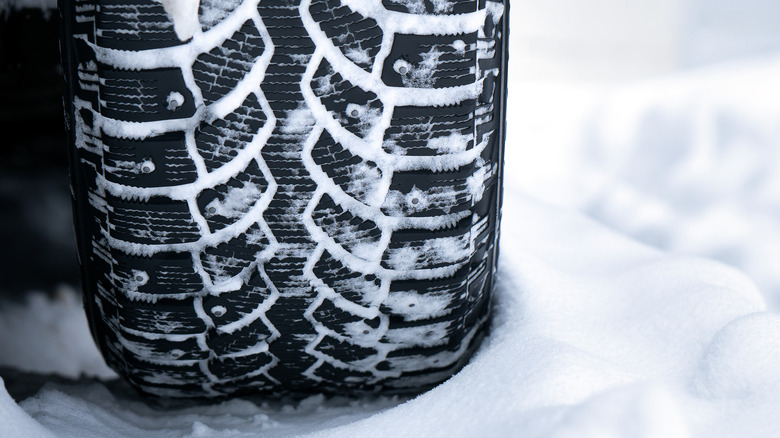 Close-up of a studded winter tire in snow.