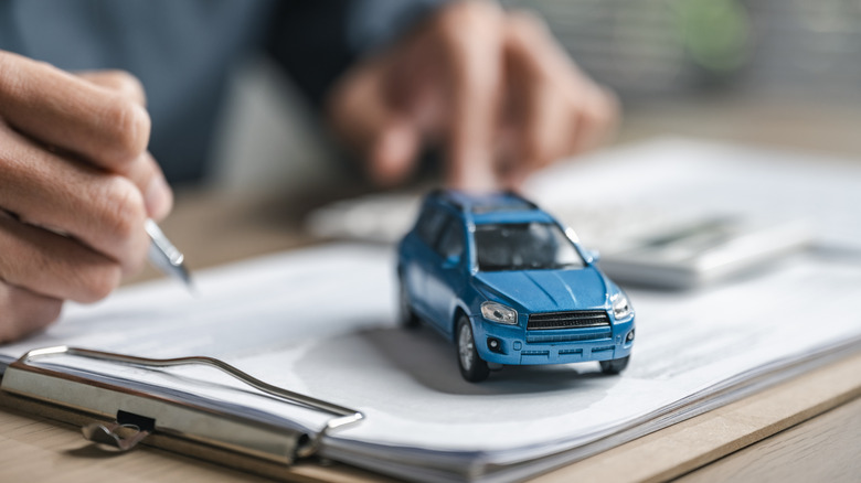 Model of an older blue Toyota RAV4 with car dealership paperwork