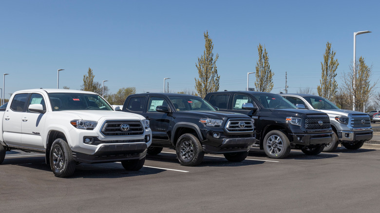 Front view of Toyota Tacoma and Tundra pickup trucks parked on a dealership lot.