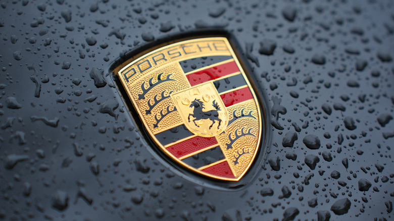 A Porsche logo on a black vehicle with water drops
