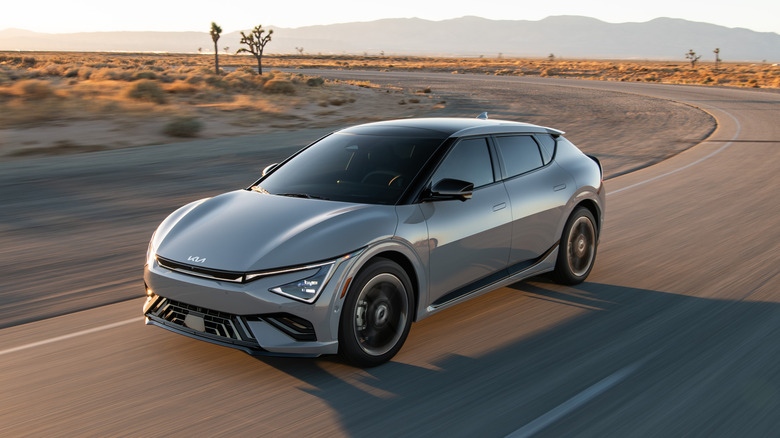 A gray 2026 Kia EV6 on a dessert road with mountains in the background