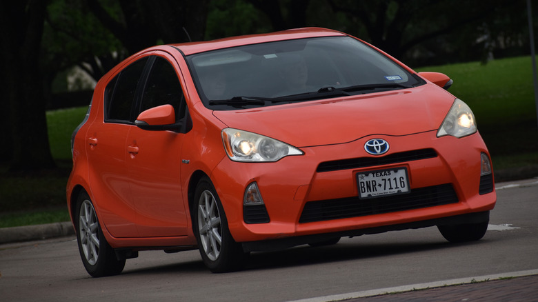 A portrait of a red-orange colored Toyota Prius economy car