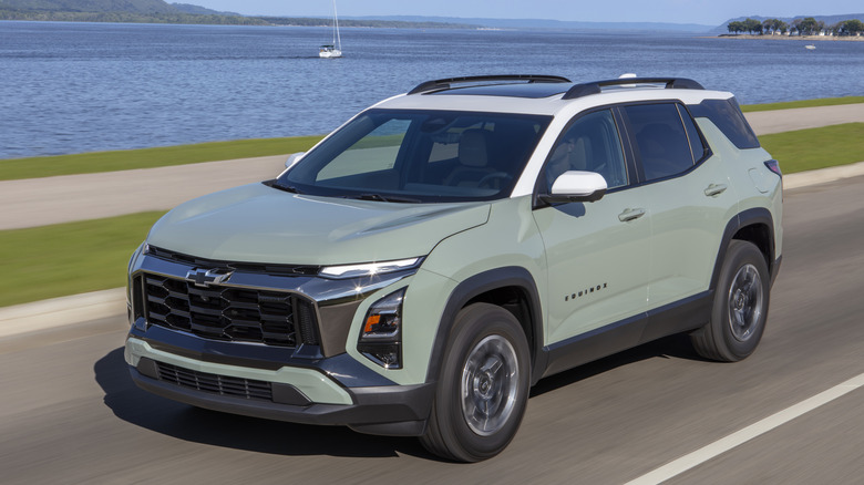 A green 2026 Chevrolet Equinox on a road with a body of water and a sailboat in the background