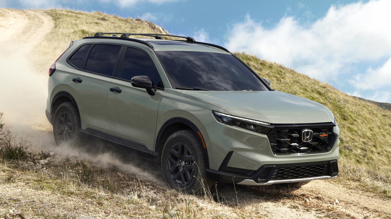 Front 3/4 view of Honda CR-V driving on dusty dirt trail downhill