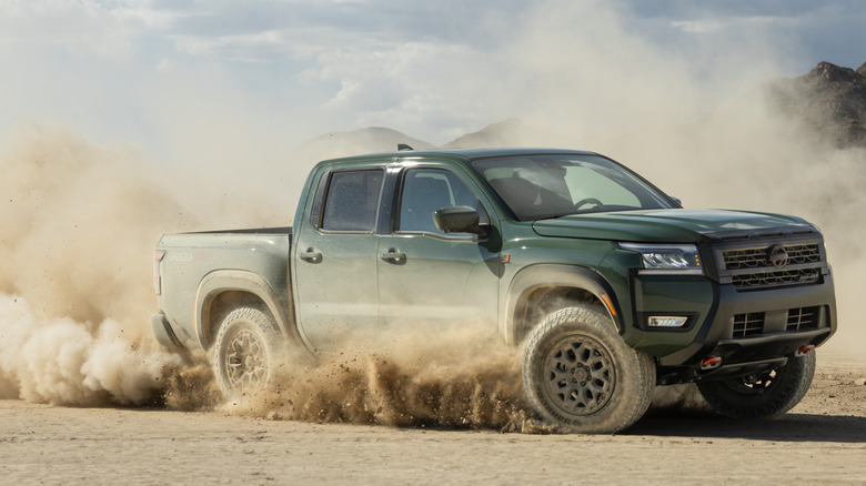 Green 2026 Nissan Frontier pickup kicking up dust in desert.