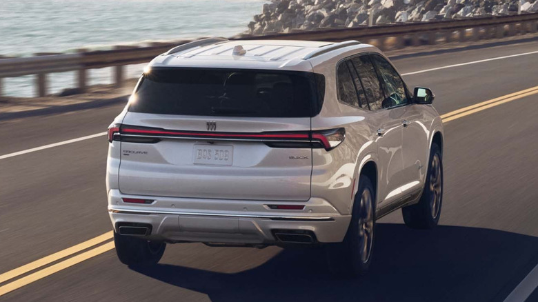 Rear 3/4 view of Buick Enclave driving on seaside roadway