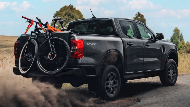 Ford Ranger pickup truck driving over a dirt road with mountain bikes in the bed