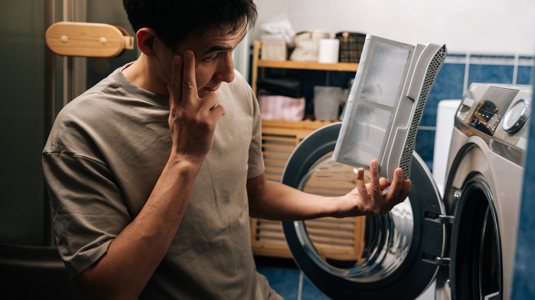Man examines lint trap from a dryer