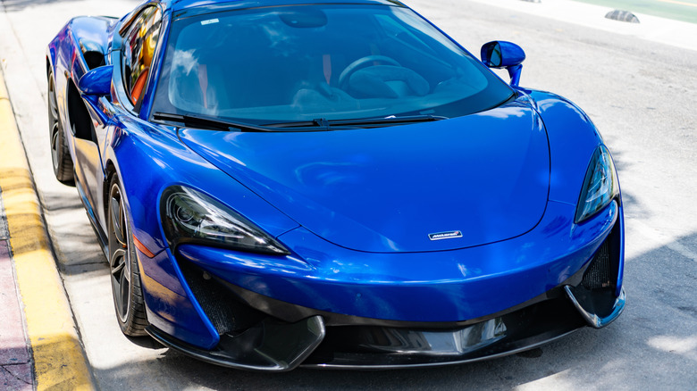 A blue McLaren sportscar parked on the side of a road.