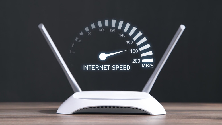 white router with two antennas placed over a wooden surface with a speedometer graphic above it highlighting fast internet speeds