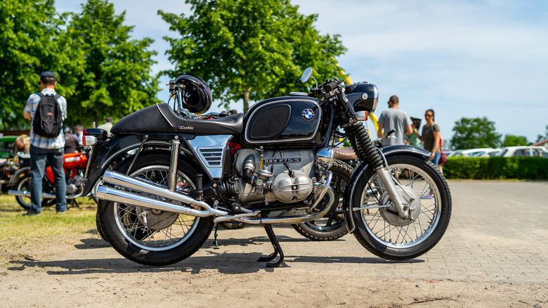 A BMW R75/5 motorcycle, parked with people in the background.