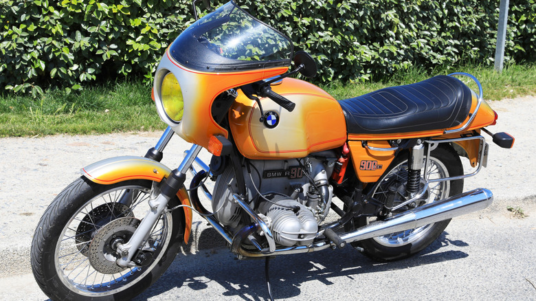 An orange sunburn BMW R90 S parked.