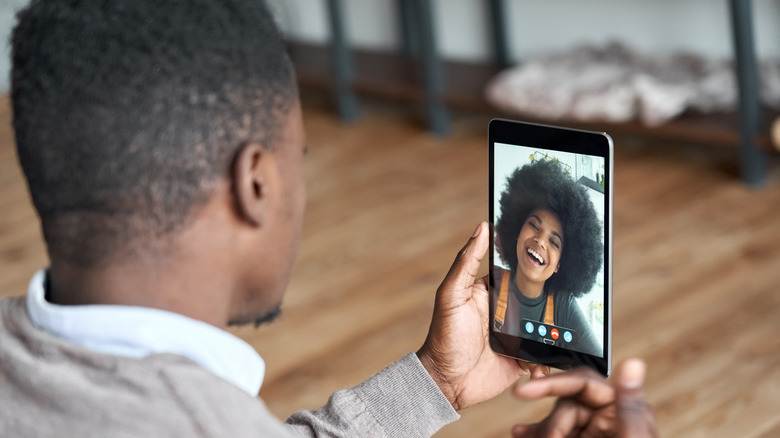 Um homem fazendo uma chamada de vídeo para uma mulher em um tablet inteligente