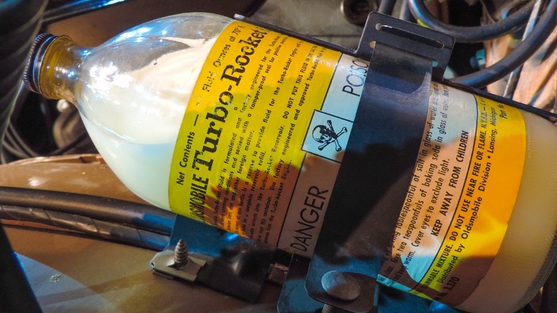1963 Oldsmobile Jetfire bottle of "Turbo Rocket Fluid" strapped inside engine bay displaying factory warning labels