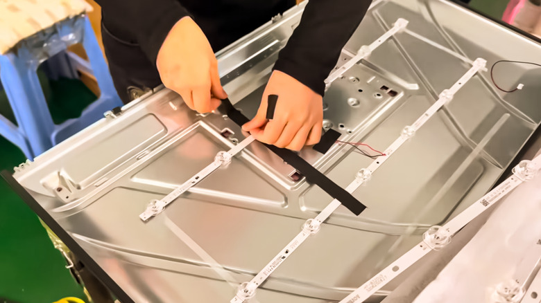 TV technicians tinkering with backlighting on an LED TV.