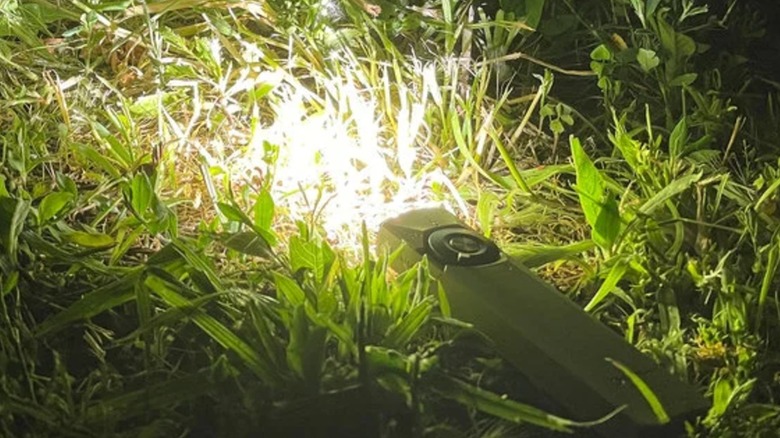 Arkfeld Ultra flashlight shining on grass.