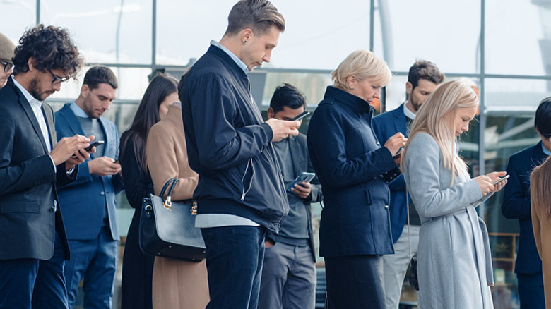 A group of people in public all looking down at their smartphones