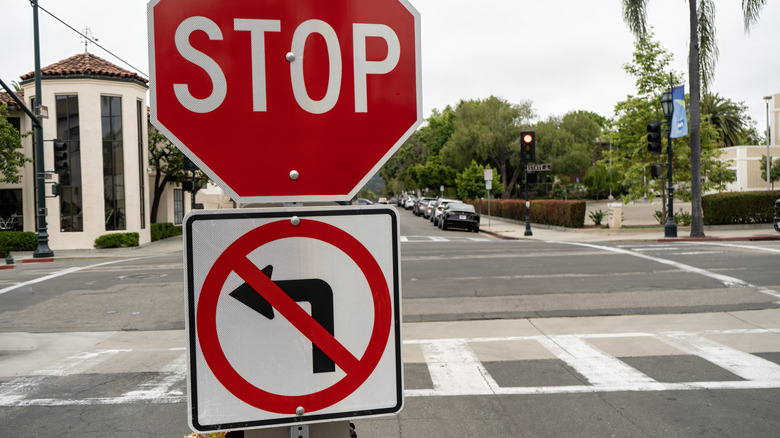 Stop sign hanging over no left turn sign