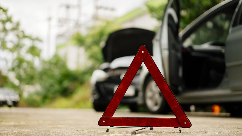 Hazard sign sitting on road in front of crashed cars