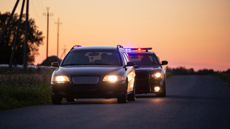 A speeding driver being chased by a police car during sunset