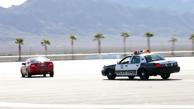 A speeding red car being chased by a police car