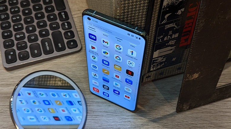 OnePlus 10 Pro with suitcase, ruler, mirror, and keyboard