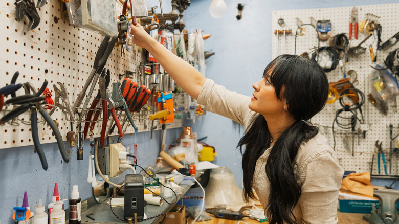 woman reaching for a tool in her workshop