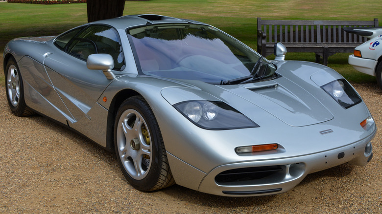 Silver 1991 McLaren F1 supercar seen from front right parked in a park