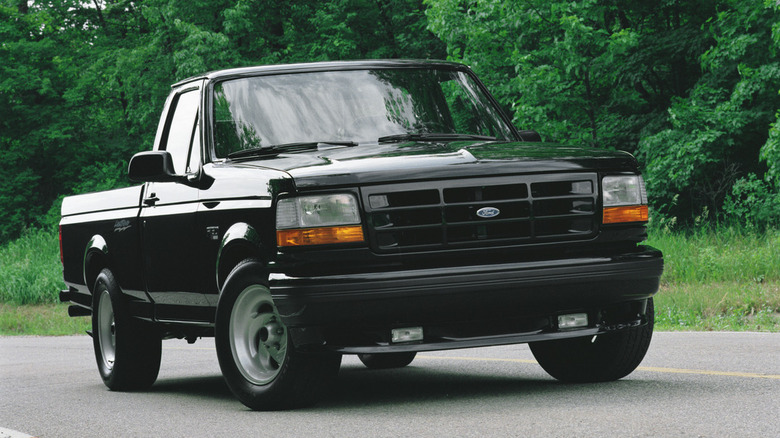 Black 1993 Ford F-150 Lightning pikcup seen from front right on a wooded road