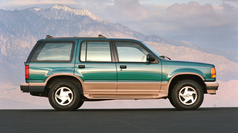 Green and tan 1993 Ford Explorer Eddie Bauer Edition SUV seen directly from the right with mountains in background