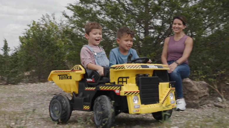 two children riding on tonka dump truck toy