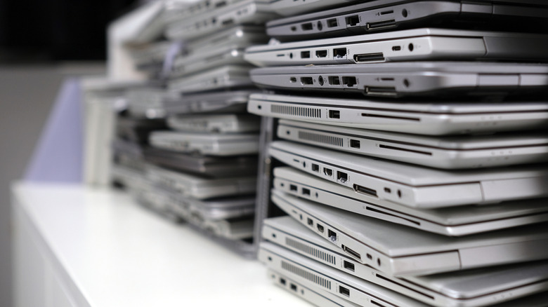 huge stack of laptops on a white table inside a room