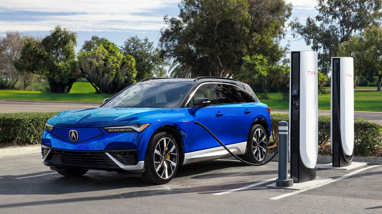 Blue Acura ZDX charging at a Tesla Supercharger
