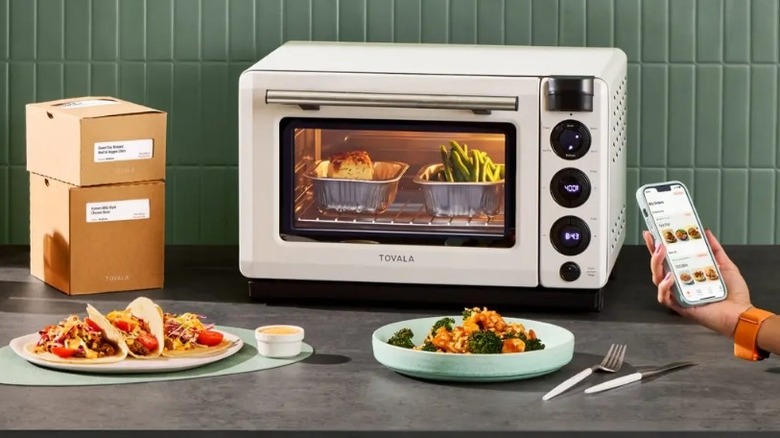 White toaster oven on a countertop surrounded by boxes and food dishes