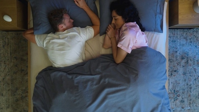 Couple lying in bed under a blue blanket