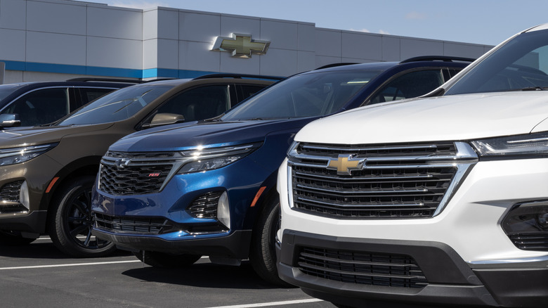 A lineuo of General Motors made cars outside a dealership.
