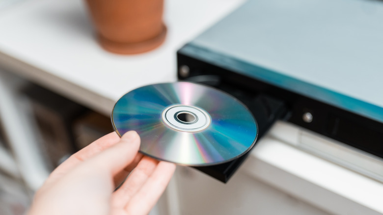 Hand holding an optical disc and dropping it onto a disc tray