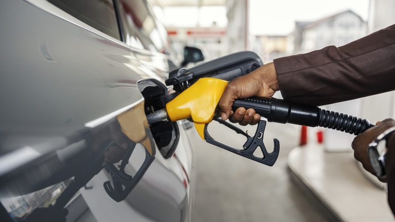 A driver fueling their car with a yellow gas pump